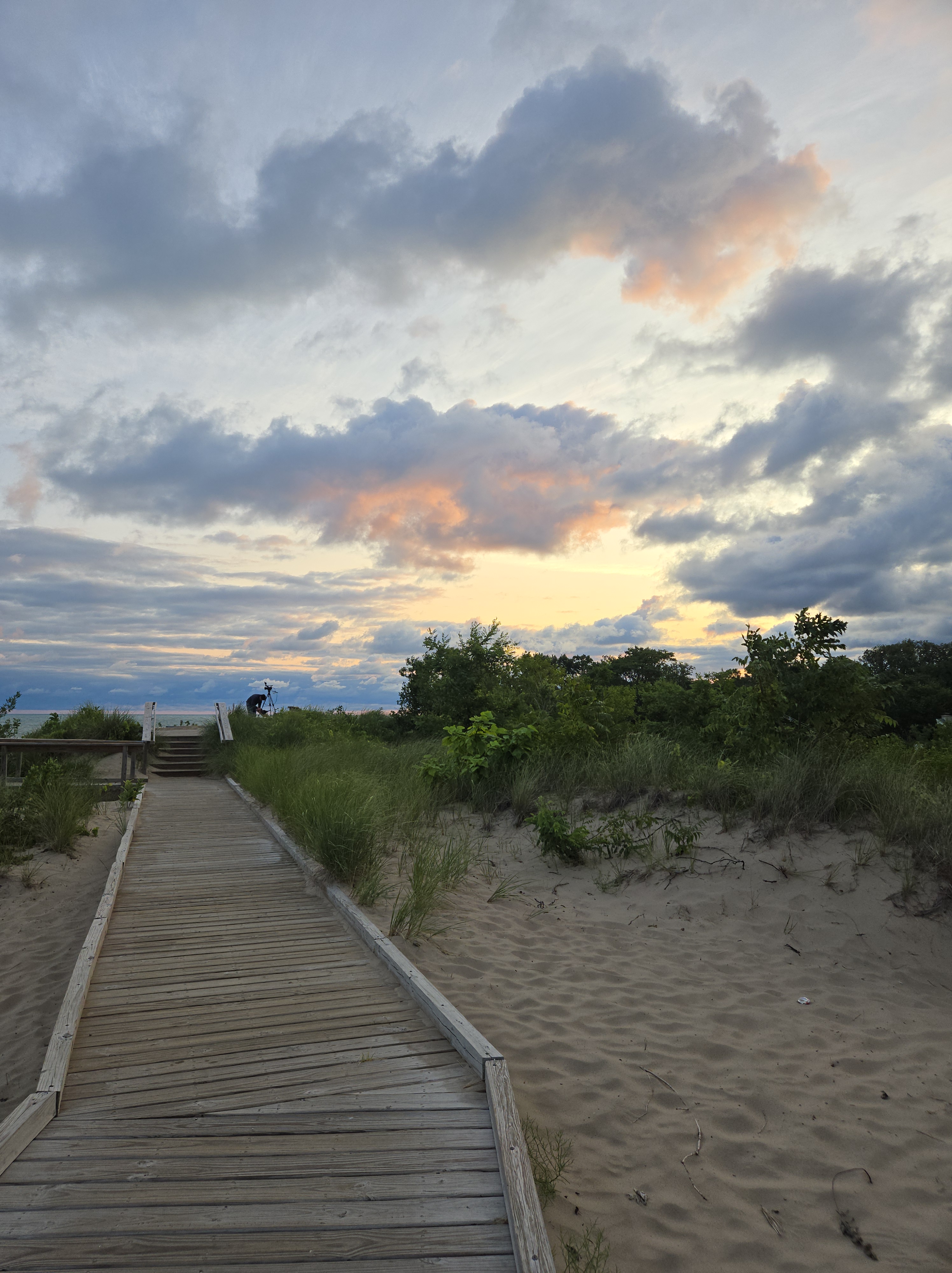 A boardwalk leading toward the horizon at sunset